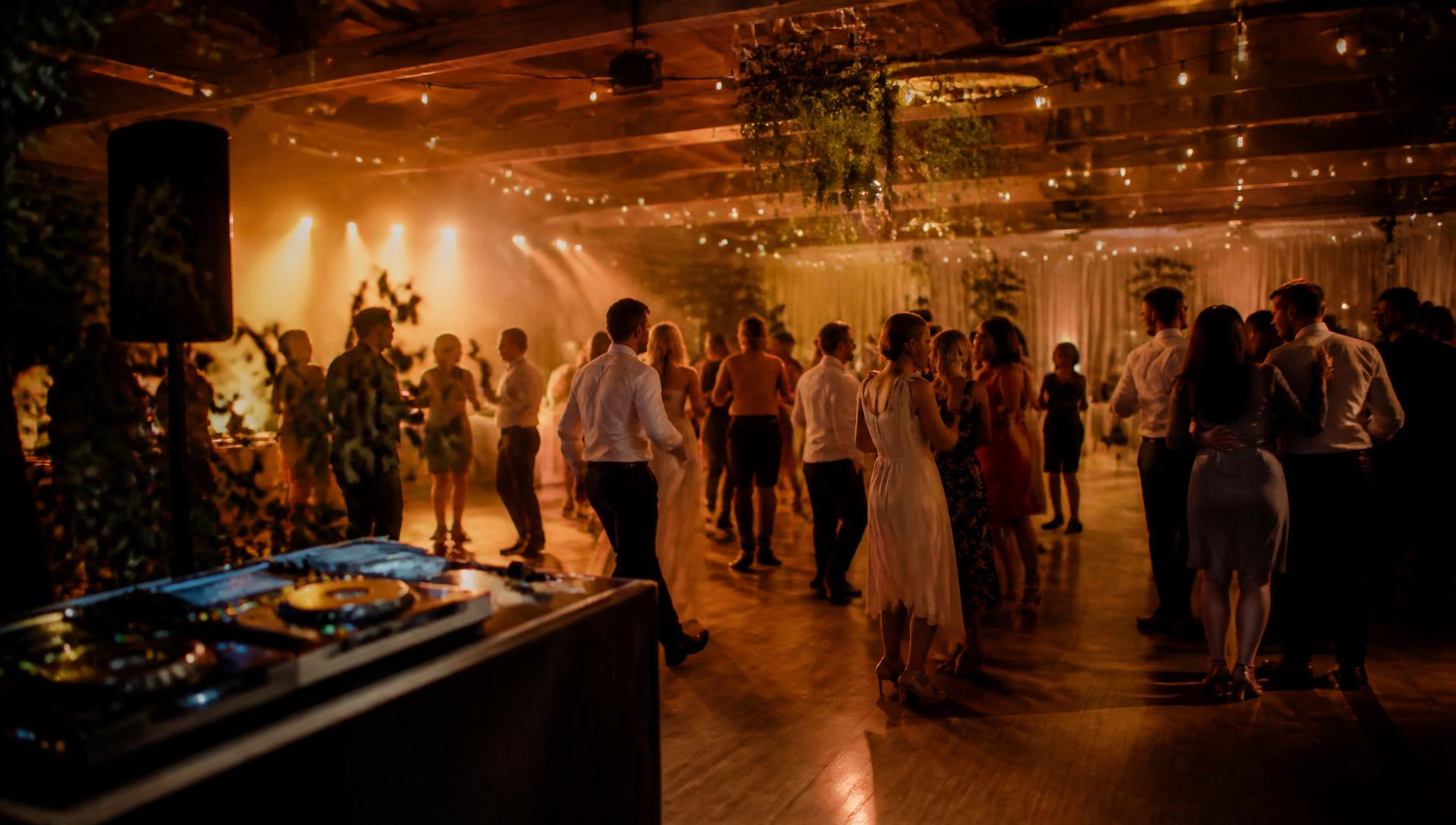 Guests dancing at an elegant event with DJ entertainment and warm ambient lighting